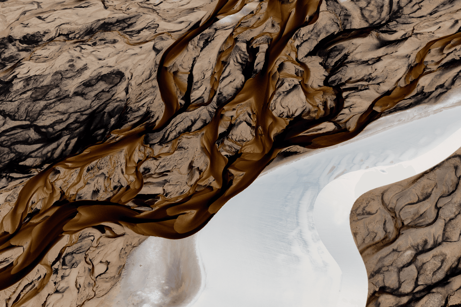 Aerial view of a river with its black waters in the middle of the white dunes, making their cuts. Lençóis Maranhenses National Park, Brazil